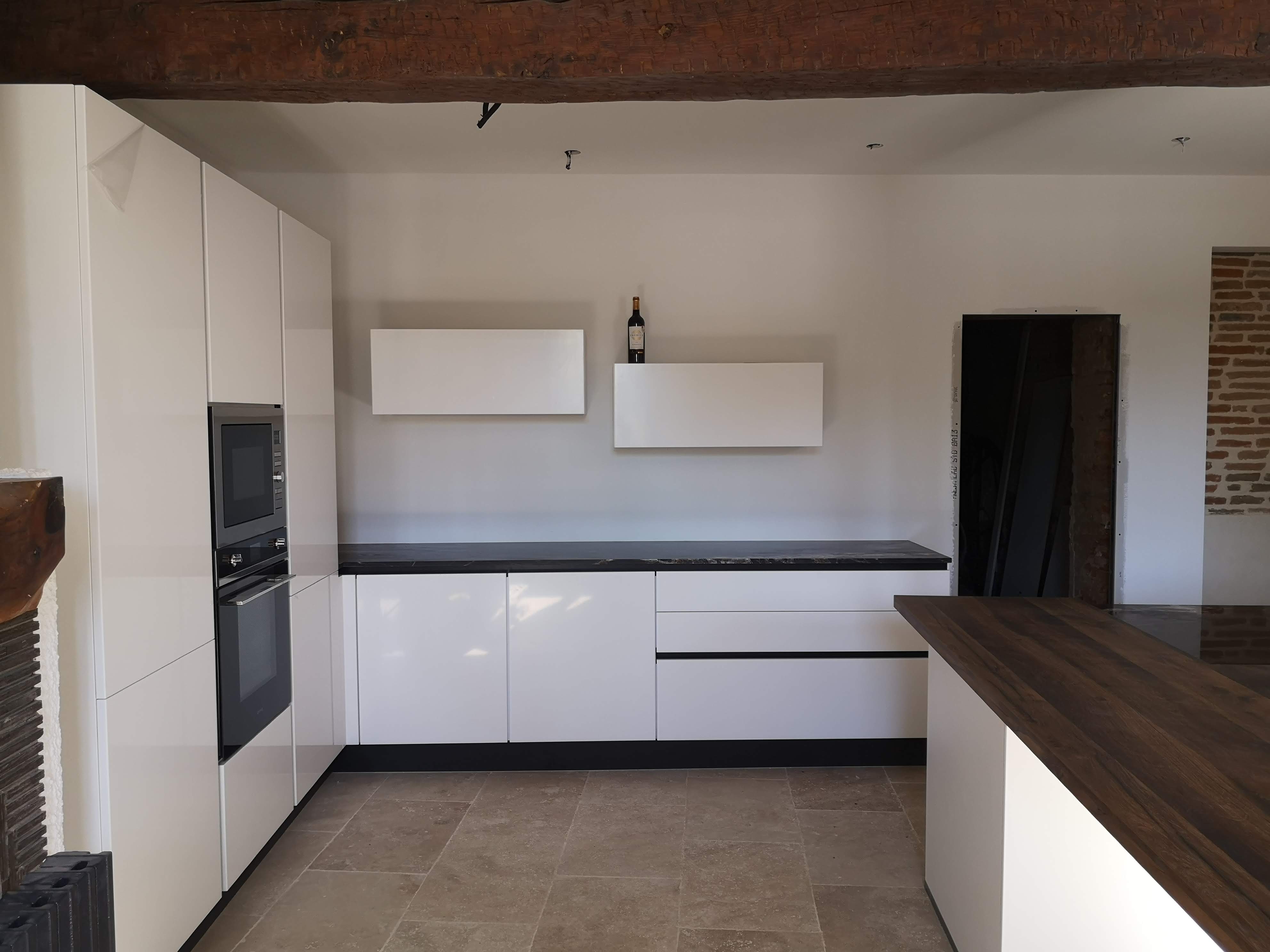 Installation d’une cuisine contemporaine blanche avec îlot et plan de travail foncé