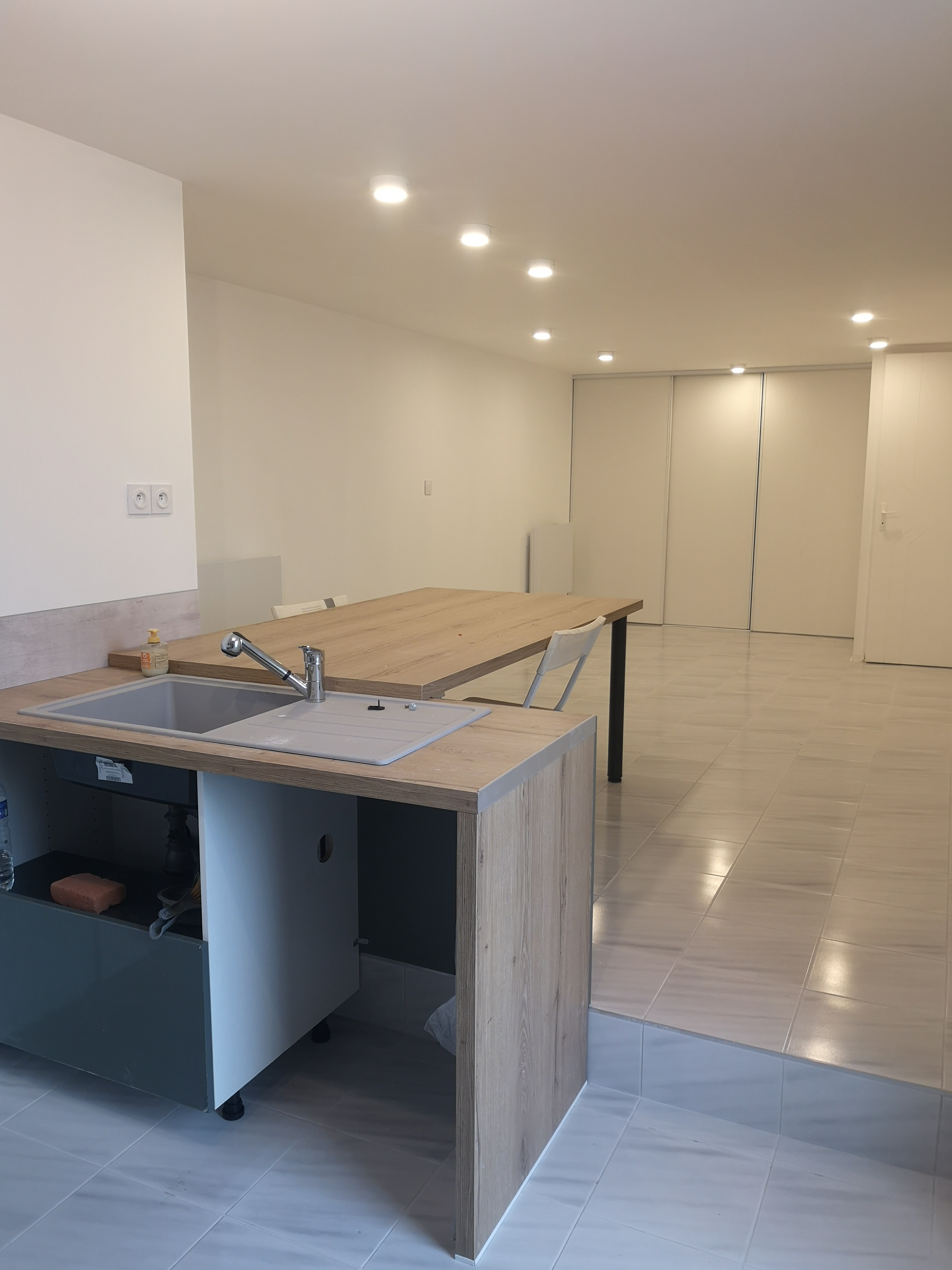 Aménagement d’une pièce de vie avec cuisine ouverte, carrelage et éclairage encastré